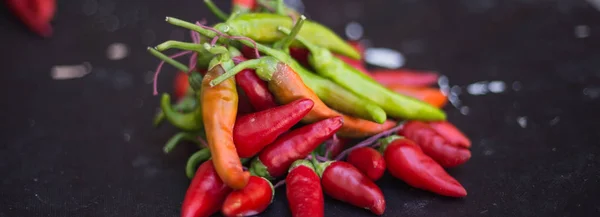 Des piments rouges à l'extérieur. Poivre rouge et vert sur fond de tableau sombre — Photo