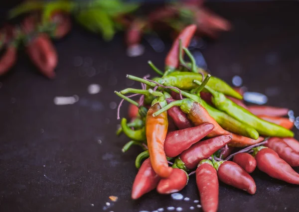 Red hot chili peppers açık havada. Karanlık kurulu arka plan üzerinde kırmızı ve yeşil biber