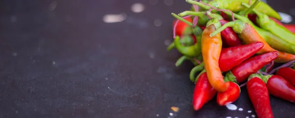 Des piments rouges à l'extérieur. Poivre rouge et vert sur fond de tableau sombre — Photo