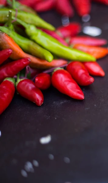 Des piments rouges à l'extérieur. Poivre rouge et vert sur fond de tableau sombre — Photo