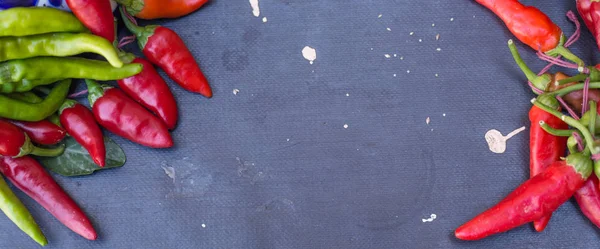 Red hot chili peppers açık havada. Karanlık kurulu arka plan üzerinde kırmızı ve yeşil biber
