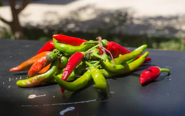 Red hot chili peppers outdoors. Red and green pepper on dark board background