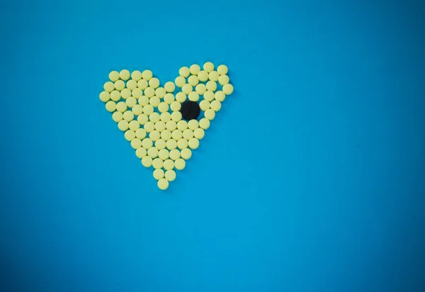 Pastillas amarillas en forma de corazón con la tableta grande negro — Foto de Stock