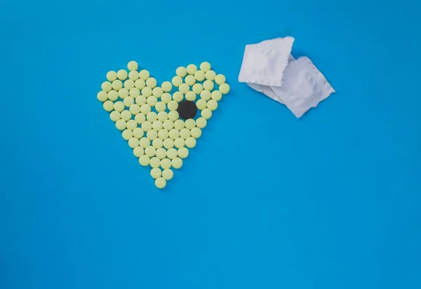 Yellow pills in shape of heart with the big black tablet — Stock Photo, Image