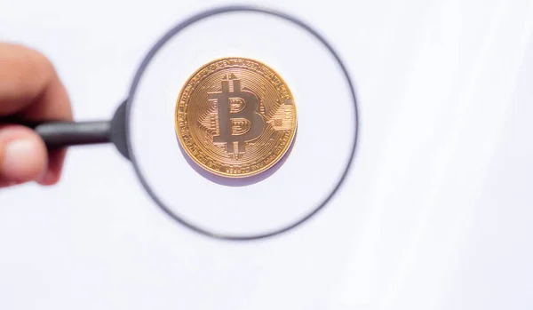 Člověk při pohledu přes zvětšovací sklo na bitcoin — Stock fotografie