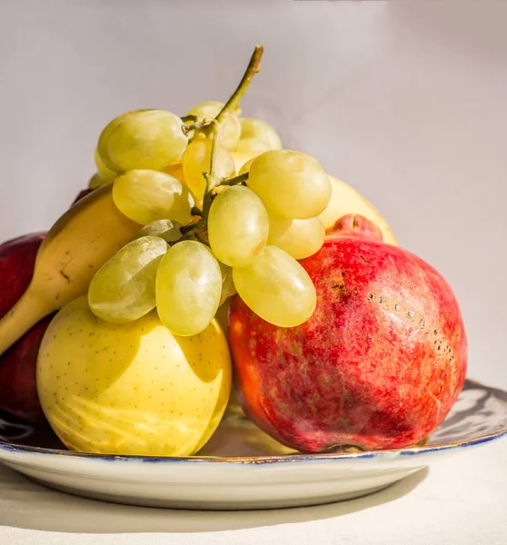 Frukt tallrik från äpple, banan, granatäpple och druvor. — Stockfoto