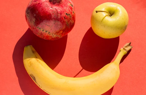 Uppsättning av granatäpple, äpple och banan på röd — Stockfoto