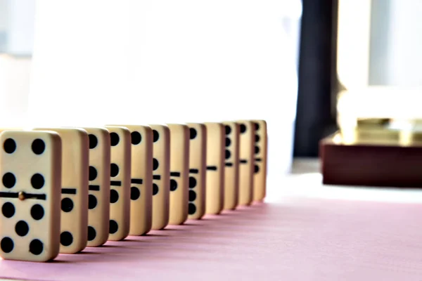 Domino-Reihe auf rosa Hintergrund. — Stockfoto