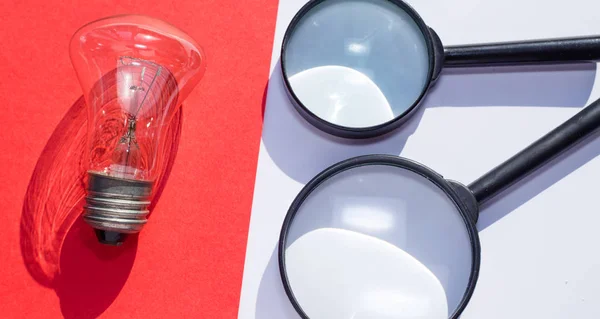 Eine Glühbirne und Vergrößerungsgläser in Rot und Weiß — Stockfoto