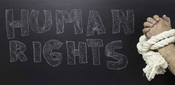 Human rights concept: chained man against the text: Human rights day written on blackboard. — Stock Photo, Image