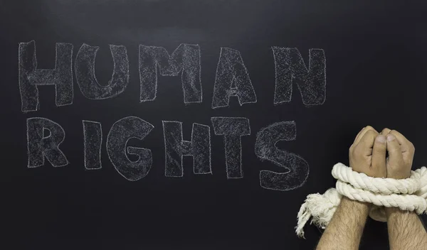 Human rights concept: chained man against the text: Human rights day written on blackboard. — Stock Photo, Image