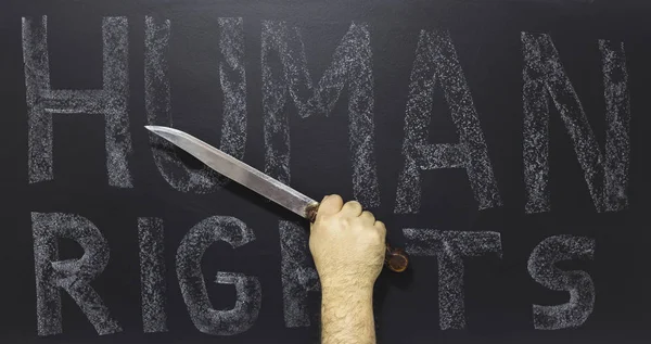 Human rights concept: Man holding knife against the text: Human rights day written on blackboard. — Stock Photo, Image