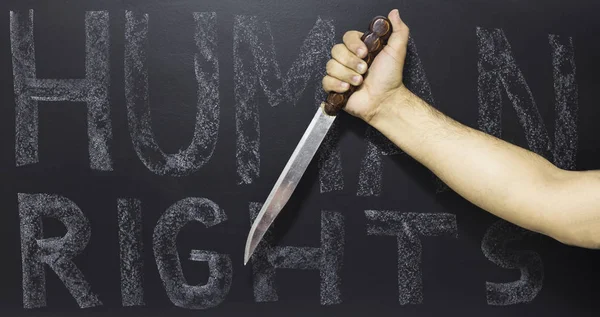 Human rights concept: Man holding knife against the text: Human rights day written on blackboard. — Stock Photo, Image