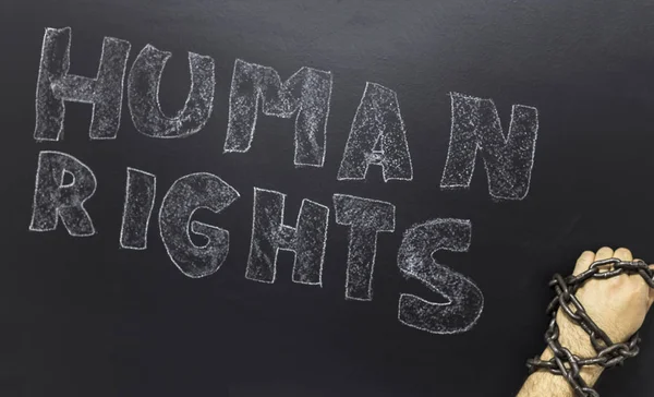 Human rights concept: chained man against the text: Human rights day written on blackboard. — Stock Photo, Image
