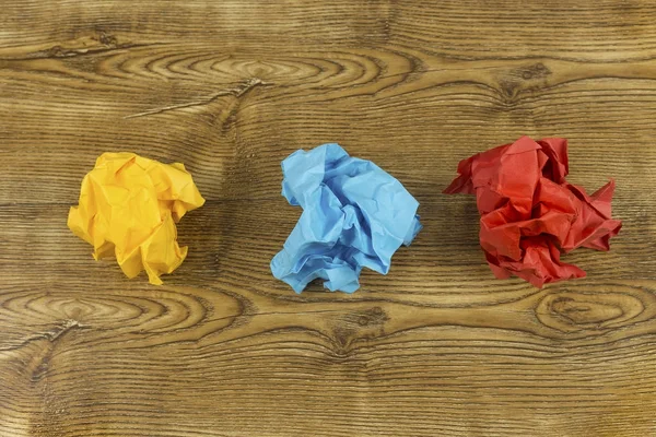 Färgade skrynkligt papper bollar på trä. Kreativitet kris koncept. Uppsättning skrynkliga gul, blått och rött papper bollar. — Stockfoto