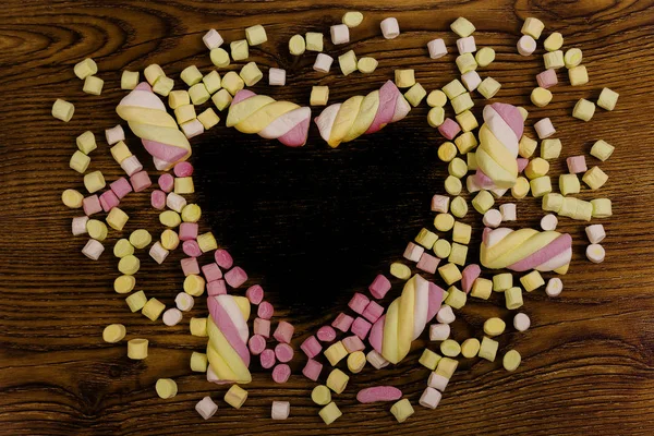 Marshmallow-Bonbons mit dunkler Herzform. Valentinstag und Liebeskonzept auf Holzgrund — Stockfoto