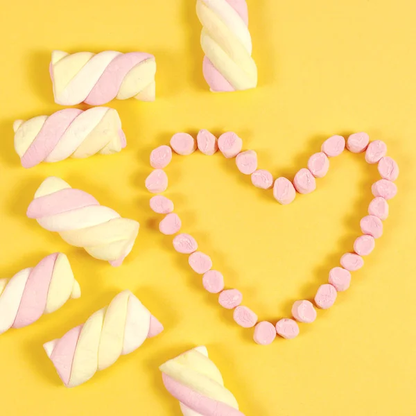 Dulces de malvavisco colocados en forma de corazón.El día de San Valentín y el concepto de amor sobre fondo amarillo — Foto de Stock