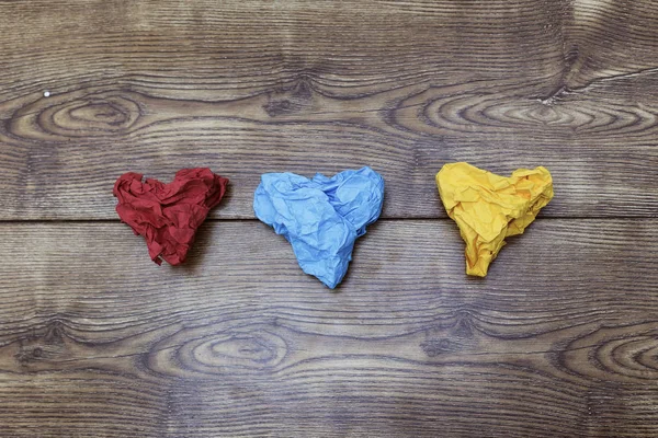 Tres coloridos papeles arrugados en forma de corazón sobre una mesa de madera. San Valentín. Día del amante. 14 de febrero concepto . — Foto de Stock