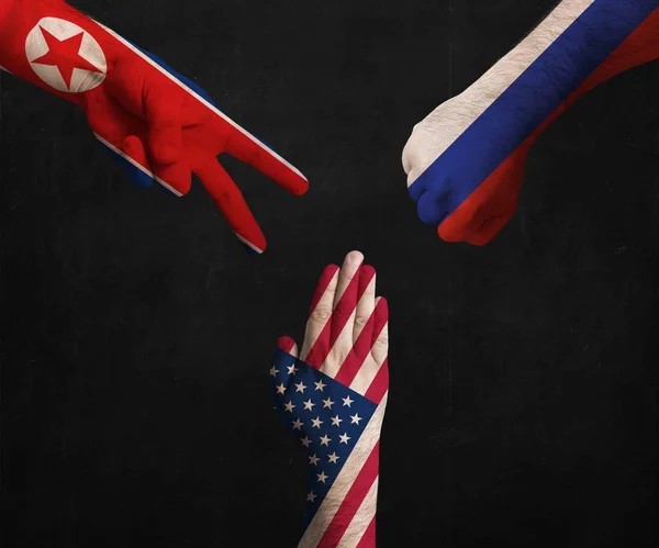 Hands decorated in flags of North Korea, USA and Russia showing Scissors, paper, stone - symbolizing the difficult political relationship. — Stock Photo, Image