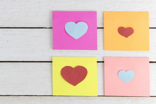 Papierowe karteczki z cięcia papieru w kształcie serca out na drewno — Zdjęcie stockowe