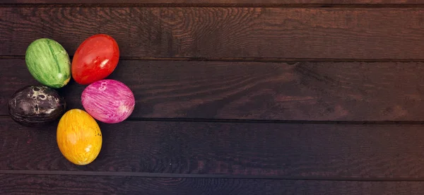 Colored easter eggs on dark wood background. View from above. Copy space for text — Stock Photo, Image