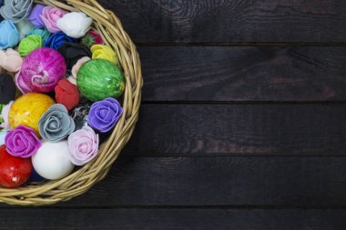 Kağıt çiçekler üzerinde koyu renkli ahşap sepet yumurta süslenmiş.