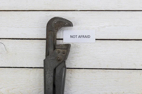Γαλλικό κλειδί σωλήνων συμπιέζει ένα κομμάτι χαρτί με μια επιγραφή να μην φοβάται — Φωτογραφία Αρχείου