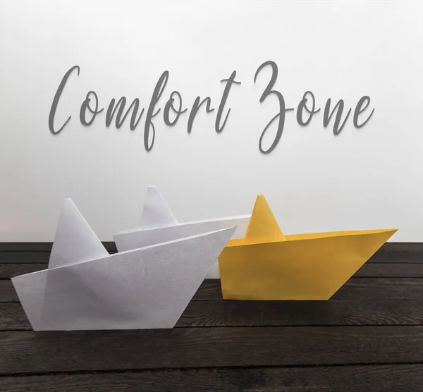 Comfort zone concept. Paper boats on wood with inscription: Comfort zone.