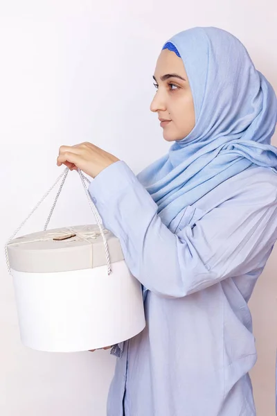Mulher muçulmana dando ou recebendo um presente em um feriado islâmico. Bonito e atraente fêmea do Oriente Médio em hijab segurando uma grande caixa de presente em mãos — Fotografia de Stock