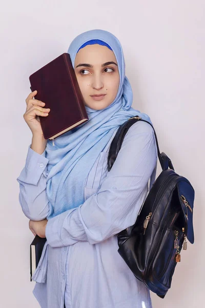 Modern Muslim student girl in hijab. Young middle-eastern college student with backpack holding books and notepads. Isolated on white background. Portrait of young Arabian woman student