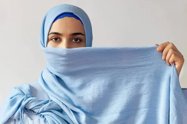Красива муслівна жінка накриває обличчя яскравою блакитною тканиною. Ісламський стиль — стокове фото