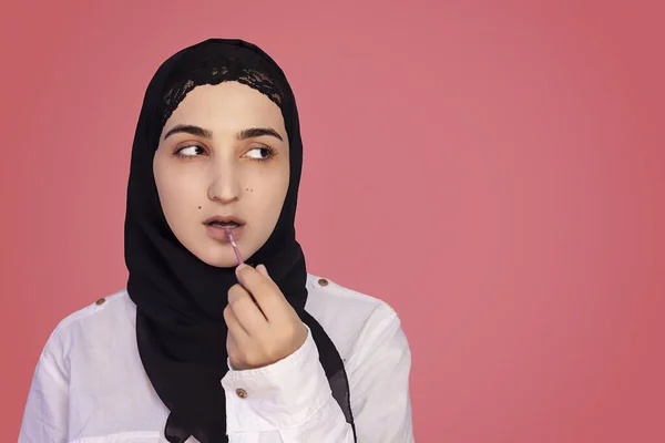 Милая 20-та самая поместила губную помаду щеткой. Прекрасна перська жінка у хіджабі макіяжує губи губною помадою. — стокове фото