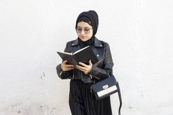 중동의 젊은 여학생 이 수첩 과 핸드백을 들고 있습니다. 전통적 인 이슬람 복장의 히잡을 입고 있는 현대 이슬람 여성 — 스톡 사진