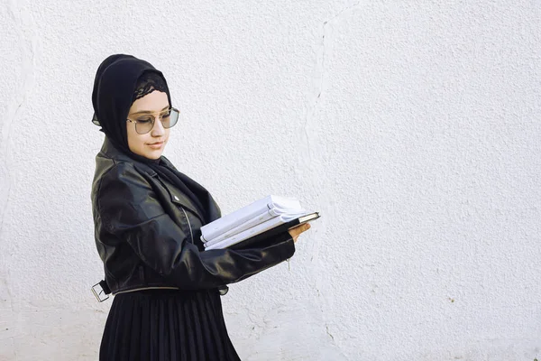 Jovem estudante do Oriente Médio menina segurando em mãos pilha de blocos de notas e sua bolsa. Mulher muçulmana moderna vestindo roupas tradicionais islâmicas hijab — Fotografia de Stock