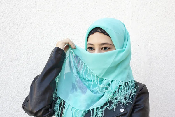 Close-up portrait of beautiful iranian girl with blue eyes. Attractive muslim woman in hijab covering her face with scarf