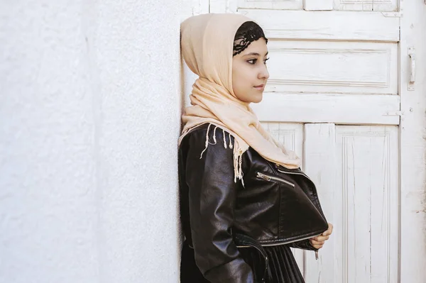 Portrait of beautiful middle-eastern girl in traditional Islamic clothing - hijab. Modern and young Iranian woman in leather jacket