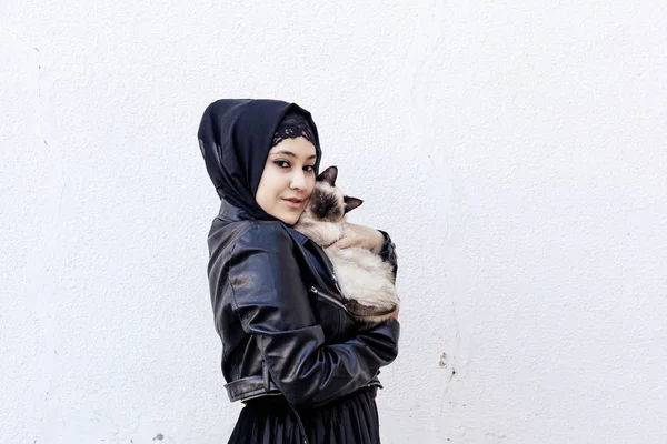 美丽的中东穆斯林女人在户外和她异国情调的暹罗猫玩耍。 爱护动物的概念 — 图库照片