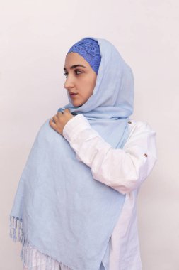 Beyaz gömlekli, parlak mavi tesettürlü zarif Müslüman kadın. Müslüman kıyafetleri içinde İranlı şık bir kız. Orta Doğulu çekici bir kadının izole edilmiş portresi.