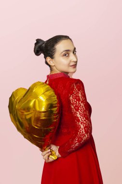Çekici İranlı bir kadın altın kalp şeklinde bir hava balonu tutuyor. Sevgililer Günü 'nü kutluyoruz. Güzel Mutlu Ortadoğulu kız. Tatil partisi, yıldönümü, doğum günü kutlaması.