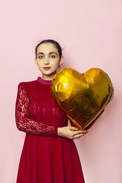 Attractive iranian woman hold golden heart shaped air balloon. Celebrating Valentines day. Beautiful Happy Young middle-eastern girl. Holiday party, Love day, anniversary, birthday celebration