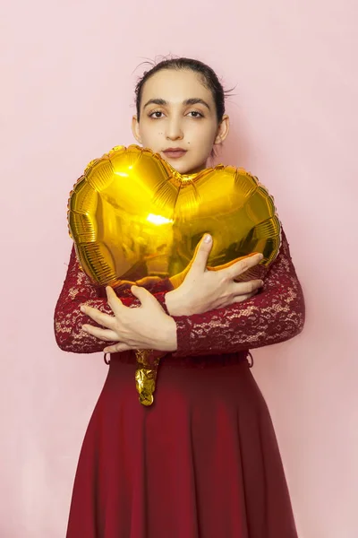 Attractive iranian woman hold golden heart shaped air balloon. Celebrating Valentines day. Beautiful Happy Young middle-eastern girl. Holiday party, Love day, anniversary, birthday celebration