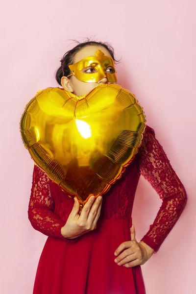 Femme portant un masque de mascarade et tenant un ballon à air en forme de coeur. Anniversaire, Anniversaire, Fête de la Saint Valentin, Fête des fêtes, Bal concepts de célébration — Photo