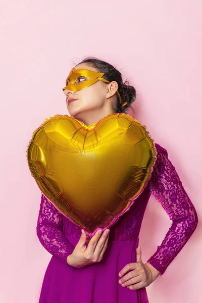 Egy nő álarcos maszkot visel és szív alakú léggömböt tart. Valentin-nap, Születésnap, Évforduló, Ünnepi, Bál ünnepi koncepciók — Stock Fotó