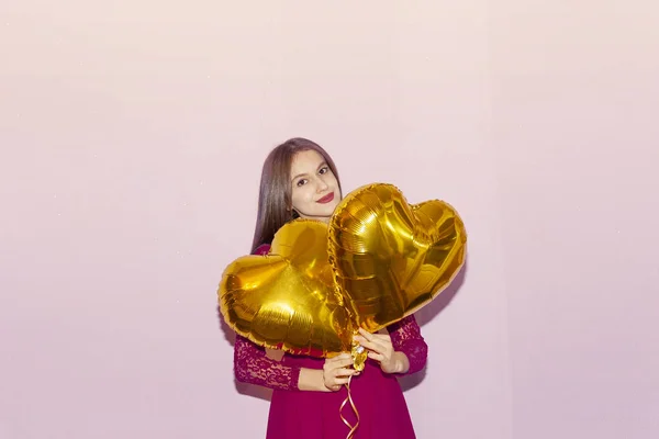 Жінка тримає золоті повітряні кулі у формі серця. День валентинки, день народження, жіночий день, річниця, концепція святкування свята — стокове фото