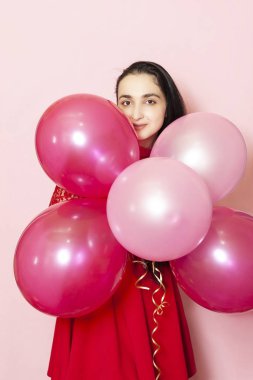 Kırmızı gece elbisesi içinde elinde balonlarla genç ve güzel bir kadın. Yirmili yaşların mutlu orta doğulu kadın portresi Sevgililer Günü, doğum günü, parti