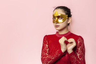 Gece elbisesi ve altın maskeli güzel bir kadının portresi. Sevgililer günü, karnaval, şenlik balosu, doğum günü kutlaması konsepti. Genç bir bayanın yüz ifadeleri