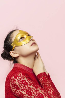 Gece elbisesi ve altın maskeli güzel bir kadının portresi. Sevgililer günü, karnaval, şenlik balosu, doğum günü kutlaması konsepti. Genç bir bayanın yüz ifadeleri