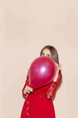 Güzel kız yüzünü hava balonuyla kaplıyor. Sevgililer günü, doğum günü, kadınlar günü, yıldönümü, bayram kutlaması konsepti