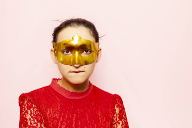 Gece elbisesi ve altın maskeli güzel bir kadının portresi. Sevgililer günü, karnaval, şenlik balosu, doğum günü kutlaması konsepti. Genç bir bayanın yüz ifadeleri