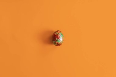Sarı arka planda tek bir altın renkli paskalya yumurtası. Yukarıdan bak. Üst Manzara. Paskalya bayramı arkaplanının düz görüntüsü